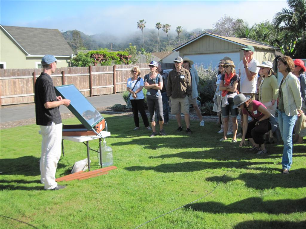 Photo of Eric Torbet, owner of Do-Right Solar, presenting the SWS-200 at the water-wise tour. View of Eric and a front view of the solar water still.